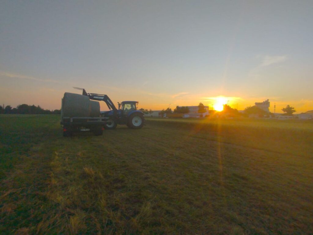 Traktor bei der Feldarbeit bei Sonnenuntergang auf den Feldern des Matzerhofs in der Nähe von Augsburg