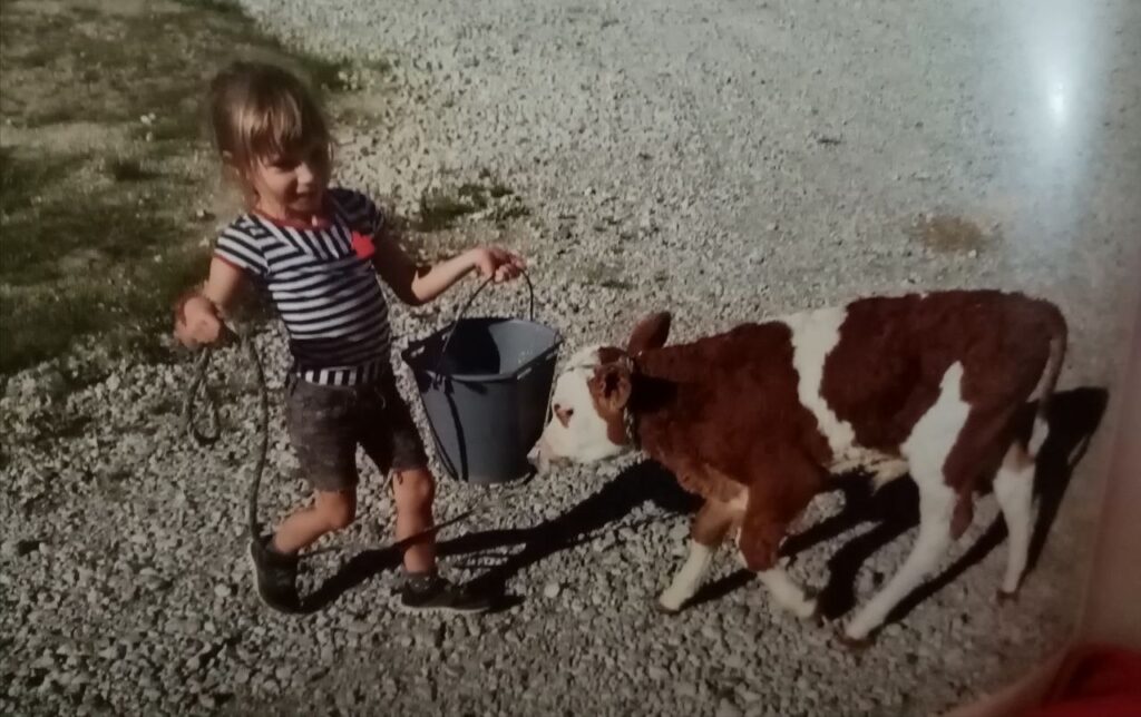 Kind führt ein Kalb mit Eimer auf dem Matzerhof – naturnahes Aufwachsen und liebevoller Umgang mit Tieren in Bayern